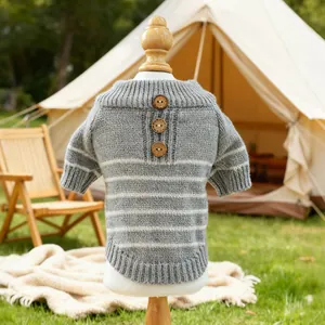 Outdoor setup of grey and white striped pet sweater with wooden buttons on wooden display