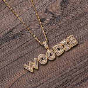 Detail of gold hip hop necklace featuring WOODIE baguette zircon pendant on rope chain