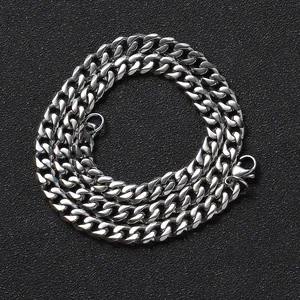 Detailed view of polished silver cuban link chain with lobster clasp on black background