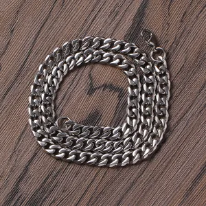 Polished silver stainless steel Cuban link necklace with lobster clasp on wood background