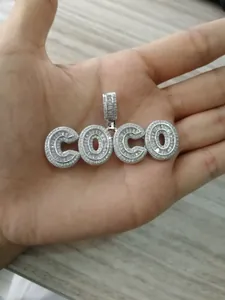 Detailed view of silver COCO pendant with micro-pave cubic zirconia on wooden background