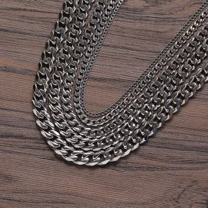 Detail view of various widths of polished stainless steel Cuban link chains on dark wood