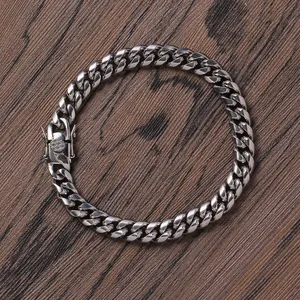 Top-down macro view of a silver polished stainless steel Cuban link bracelet with box clasp