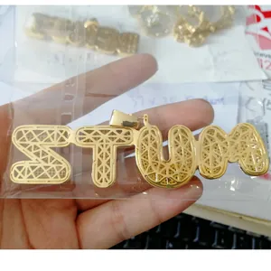 Close-up of golden bubble-style STUM letter pendant with inlaid cubic zirconia stones