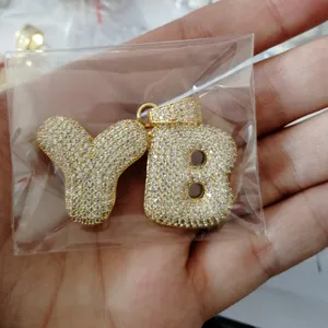 Macro view of gold plated hip hop pendant with cubic zirconia micro pave lettering