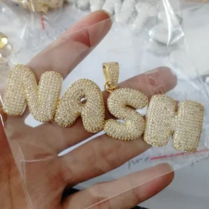 Close-up of golden NASH bubble letter pendant with handset cubic zirconia stones