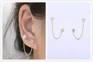 Detail of s925 silver double ear hole chain earring with gold finish and zircon