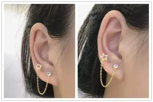 Detail showing gold double piercing earring with star and square chain link designs