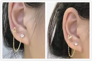 Detail of gold chain earrings for double piercings featuring butterfly and triangle motifs