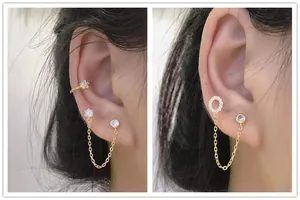 Detail of gold-plated S925 silver double piercing earrings with CZ chain on female model