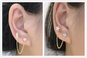 Detail view of gold S925 silver double piercing earrings with star and leaf zircons