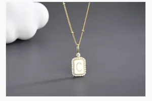 Detailed close-up of golden necklace pendant with letter C and sparkling zircon border