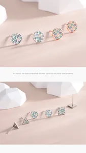 Detailed view of geometric silver earrings with green and blue checkered patterns