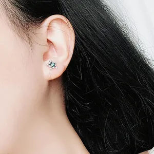 Elegante zilveren ster oorbel met blauwe zirkoon gedragen door een model
