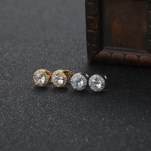 Detailed view of gold and silver halo stud earrings with round zircons on a dark surface