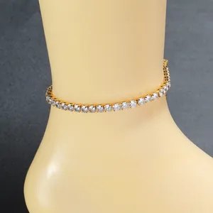 Primer plano de una tobillera de tenis dorada con circonitas brillantes en el tobillo