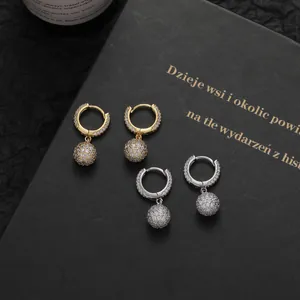 Close-up of gold and silver hoop earrings with pave-set zircon spheres on dark background
