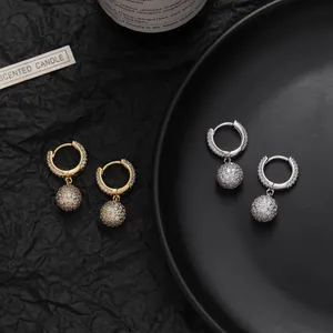 Detailed view of gold and silver hoop earrings with micro-pave zircon sphere charms