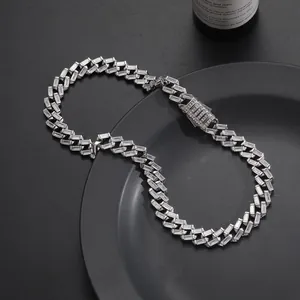Macro view of 12mm silver Cuban link chain with baguette-cut zircons on dark background