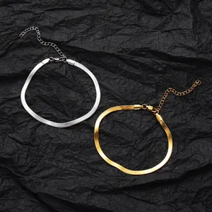 Close-up of gold and silver snake bone chain anklets with lobster clasp on black background