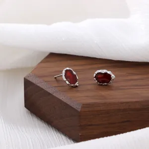 Textured silver studs with deep red gemstones on elegant dark wood and white fabric