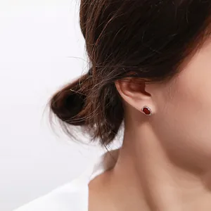 Detail view of red ruby earrings with silver wavy metal texture on a female model