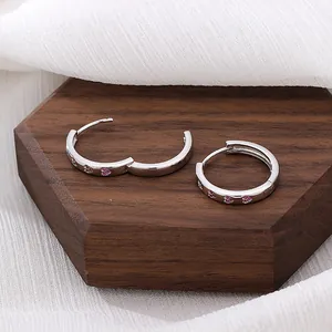 Orecchini a cerchio in argento S925 con pietre rosa su espositore in legno scuro