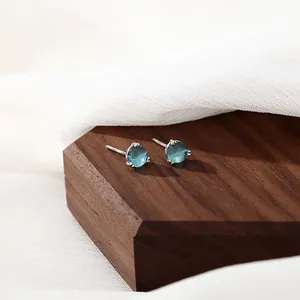 Elegant S925 sterling silver stud earrings with round light blue gemstones on wood