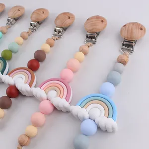 Close-up of Morandi colored silicone and wooden pacifier clips with rainbow charms