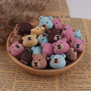 Colorful bear-shaped silicone beads for DIY jewelry and crafting projects in a wooden tray