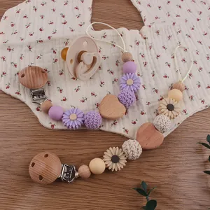 Macro detail of handmade beech wood and silicone baby pacifier clips on floral fabric