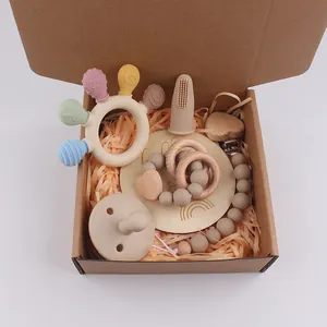 Silicone baby teether and pacifier gift set with wooden accessories in a brown box