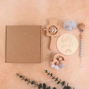 Close-up of wooden baby rattle set with silicone pacifier and engraved milestone card