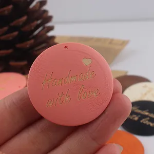 Detailed close-up of a pink round wooden tag engraved with Handmade with love and heart