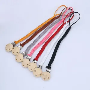 Détail d'attaches-tétines tressées colorées avec boucles en bois rondes et clips en métal
