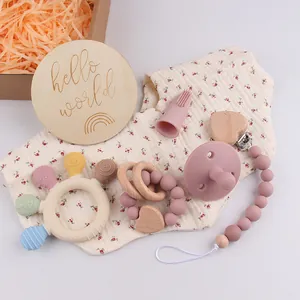 Flat lay of pink silicone baby teethers and pacifier set in a rustic wooden gift box