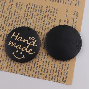 Detail of round matte black wooden tags with Handmade engraving and smiley face logo
