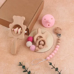 Detailed close-up of a beech wood bear rattle and pink silicone pacifier clip set