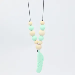 Détail du collier de dentition avec pendentif plume vert menthe et perles en bois