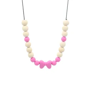 Détail du collier de dentition pour bébé avec nœud en silicone rose et perles en bois