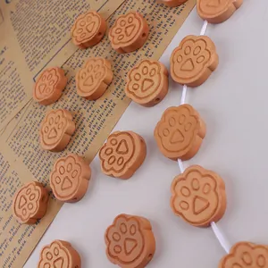 Detailed macro view of wooden cat paw beads for DIY crafting with smooth engraved patterns