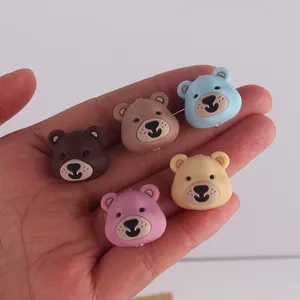 Detailed view of colorful silicone cartoon bear beads for DIY jewelry making on palm