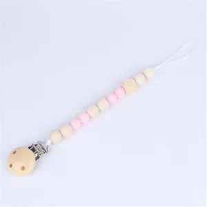 Close-up of wooden pacifier clip with pink silicone beads and metal clothing fastener