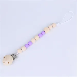 Detail of baby pacifier clip with natural wooden beads and purple silicone accents