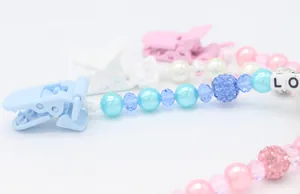 Detail of macaron blue pacifier clip featuring LOVE letter beads and sparkling crystals