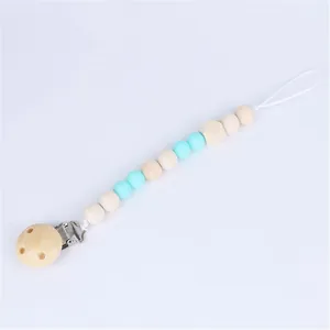 Detail of wooden pacifier clip with light blue silicone beads and polished metal clasp