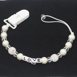 Detail of white faux pearl pacifier clip with LOVE letter beads and crystal accents