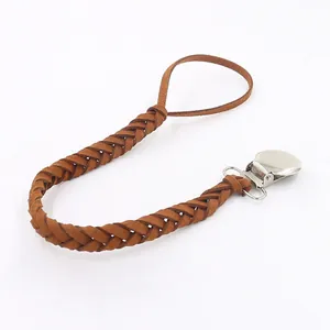 Detail of hand-woven dark brown leather pacifier clip with secure silver metal duckbill buckle