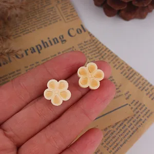Close-up of small wooden flower charms with orange heart petals for DIY jewelry making