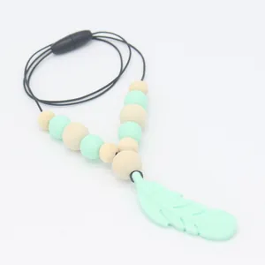 Détail du collier de dentition avec pendentif plume en silicone vert menthe et perles bois
